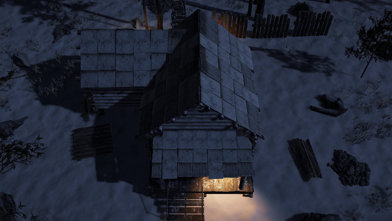 The same cabin at night with warm orange light falling from under the eaves across the porch and onto the snow.